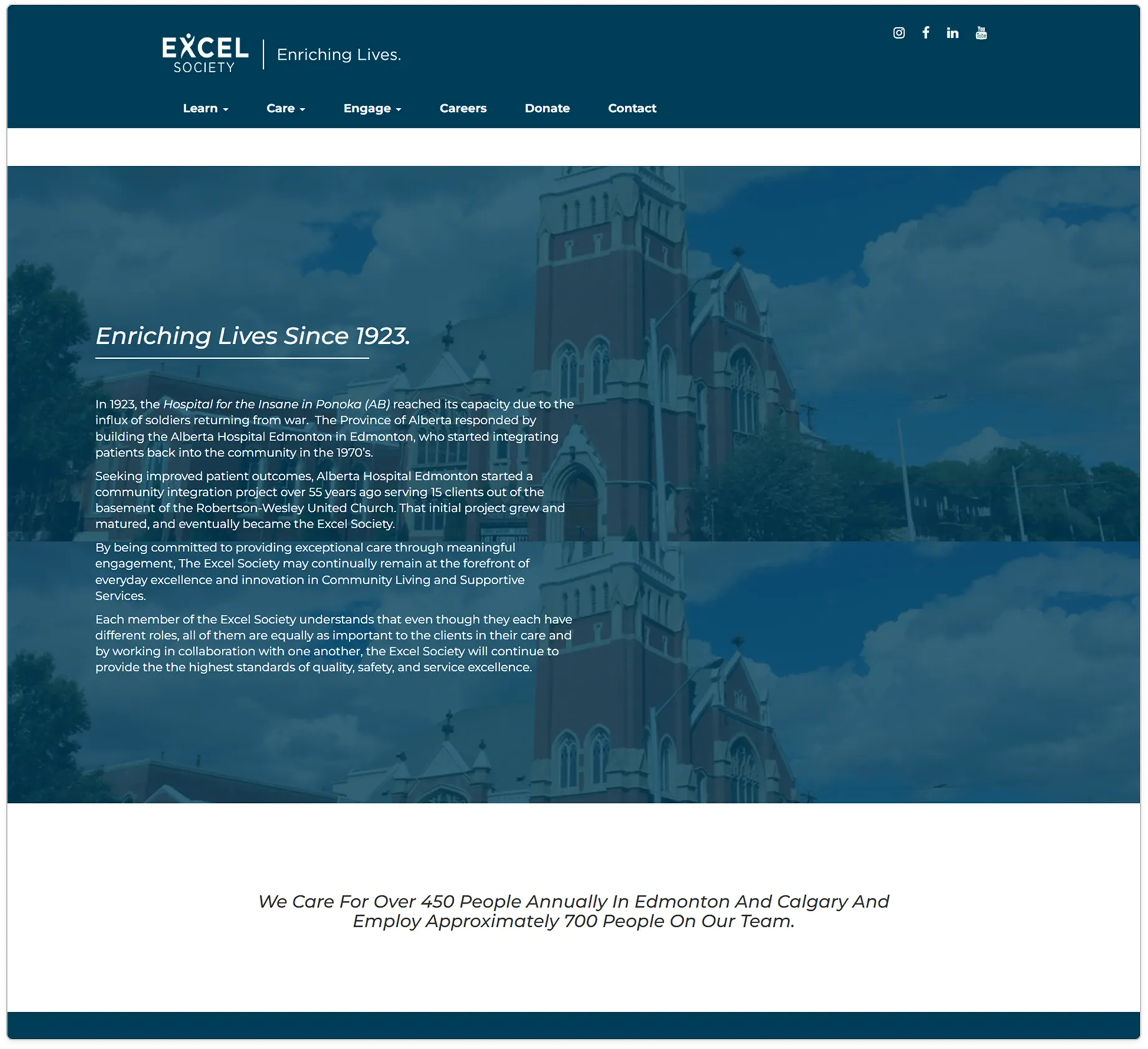 Excel Society's original About page: a faded photo of a red-brick church behind the heading 'Enriching Lives Since 1923', then several paragraphs of history.